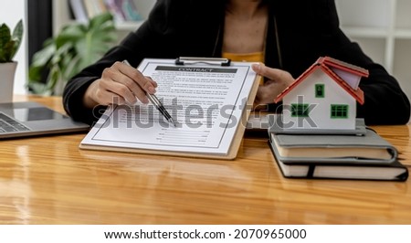 The property salesperson points to the sign box on the purchase agreement, the customer agrees to sign the sale after listening and reading the details of the agreement. Real estate trading ideas.