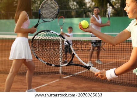 Happy family playing tennis on court outdoors, closeup