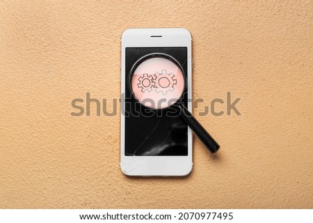 Mobile phone with broken screen, magnifier and paper sheet with drawing of gears on color background