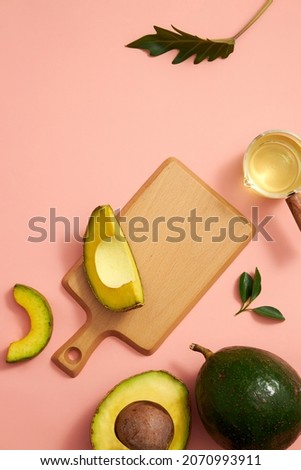 Avocado extract in chopping board with green leaf , blank space for advertising pink pastel background , top view , photography experiment concept