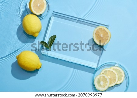 Lemon and sliced lemon in petri dish transparent podium blue background with water wave and water drop , top view , for food advertising
