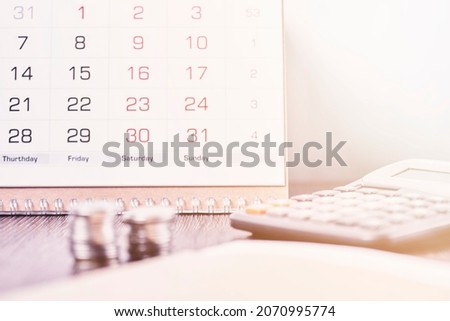 Calendar, calculator and stack of coins in office. Deadline concept. Calendar, coins and calculator on table. Business, finance, taxes, accounting, wages, payroll or money planning concepts