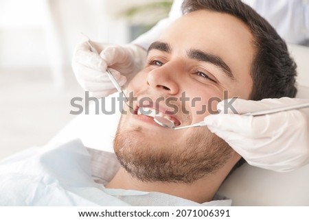 Dentist examining teeth of young man in clinic Royalty-Free Stock Photo #2071006391