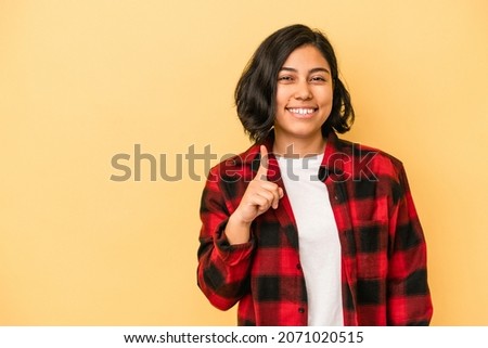 Young latin woman isolated on yellow background showing number one with finger.