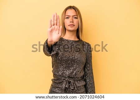Young caucasian woman celebrating new year isolated on yellow background standing with outstretched hand showing stop sign, preventing you.