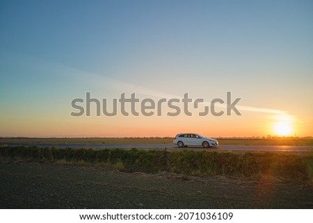Aerial view of intercity road with blurred fast driving environment friendly electric car at sunset. Top view from drone of highway traffic in evening. Royalty-Free Stock Photo #2071036109