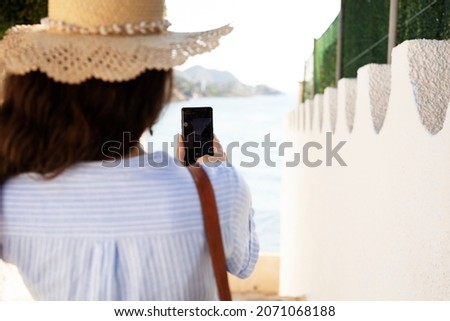 Young woman taking photo with phone near the sea. Happy woman enjoy in sunny day	