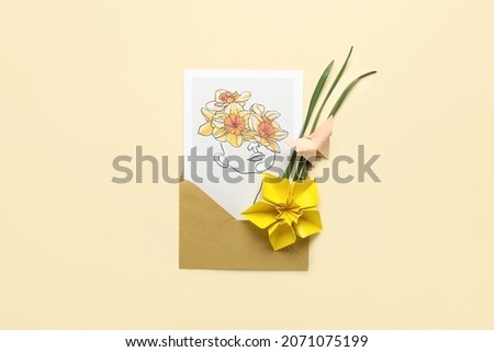 Origami narcissus flower and envelope with greeting card on color background
