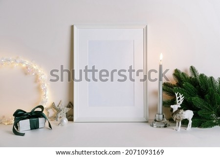 Mock up frame with Christmas decorations. Christmas composition with fir tree branch, deer, candle and silver stars on white background. Winter festive concept. Template