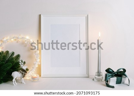 Mock up frame with Christmas decorations. Christmas composition with fir tree branch, deer, candle and silver stars on white background. Winter festive concept. Template