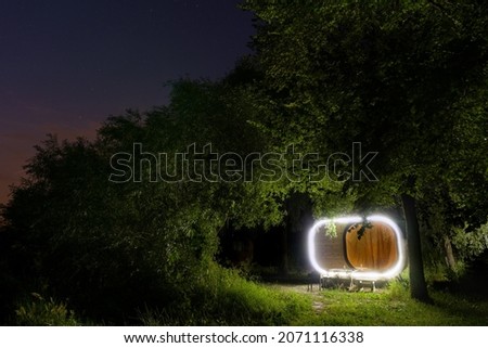 A small house in the woods, lots of light. Starry night.