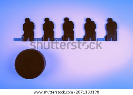 Silhouettes of five ice hockey players and one puck on a blue background.