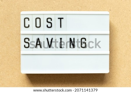 Lightbox with word cost saving on wood background