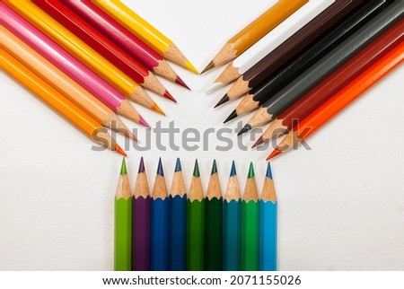Top view photo of various colored pencils. placed on a white background and bright colored pencils placed alternately on left, right and bottom in close-up, top view of concept art, text and  copy spa