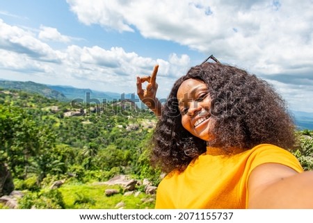 african young woman taking a selfie outdoors against a nature landscape