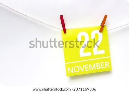 November 22nd. Day 22 of month, Calendar date. Paper cards with calendar day hanging rope with clothespins on white background. Autumn month, day of the year concept