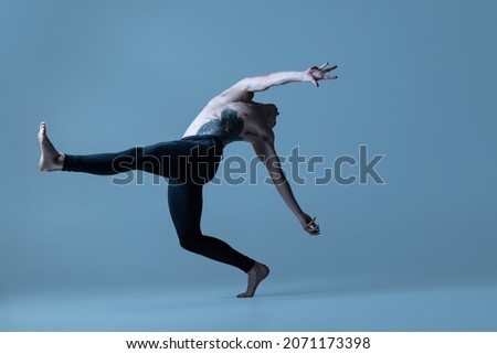 Language of body. Portrait of young man, flexible male ballet dancer dancing isolated on old navy background. Art, motion, action, flexibility, inspiration concept. Flexible artist. Beauty of male Royalty-Free Stock Photo #2071173398