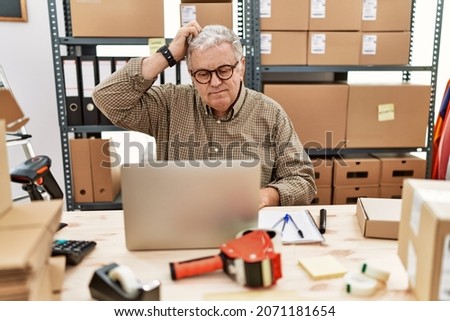 Senior caucasian man working at small business ecommerce with laptop confuse and wonder about question. uncertain with doubt, thinking with hand on head. pensive concept. 