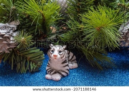 The water tiger is the symbol of the Chinese year 2022. A figurine of a tiger lying on a blue shiny background