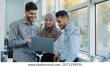Multiethnic colleagues listens Arabic team leader explain corporate task application to diverse workers indian businesspeople looking on laptop screen working together, teamwork brainstorm concept Royalty-Free Stock Photo #2071198934