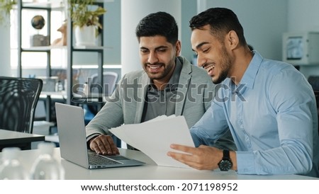 Cheerful positive friendly businessmen partners colleagues holding document contract looking at laptop screen discuss ideas having fun during break in office. Good business relationships, concept Royalty-Free Stock Photo #2071198952