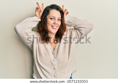 Young caucasian woman wearing casual clothes posing funny and crazy with fingers on head as bunny ears, smiling cheerful 
