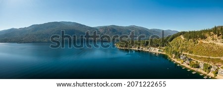 Aerial panoramic view of a residential homes by a lake and mountains. Taken at Christina Lake, East Kootenay, British Columbia, Canada. Royalty-Free Stock Photo #2071222655