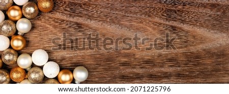 Christmas or New Years corner border of gold and white decorations. Above view on a dark rustic wood banner background. Copy space.