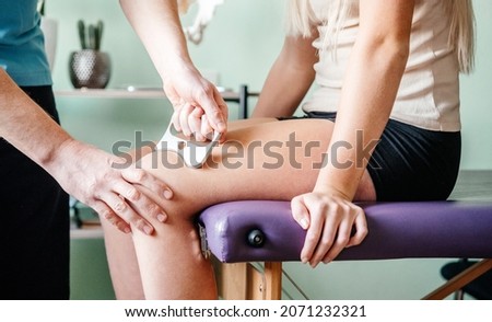 Therapist using IASTM instrument treatment, girl receiving soft tissue treatment on her leg with guasha stainless steel tool, osteopathy Royalty-Free Stock Photo #2071232321