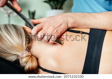 Chiropractor performing myofascial release techniques with IASTM tool for the Rhomboid muscle to relieve scapular pain Royalty-Free Stock Photo #2071232330