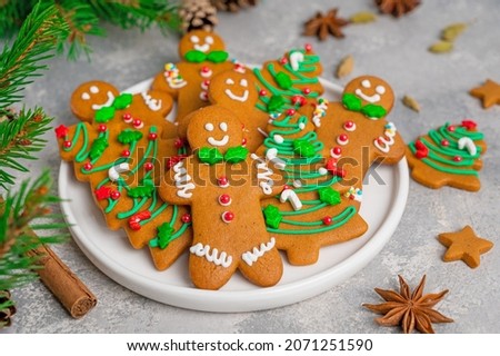 Gingerbread cookies in the form of man and christmas trees decorated with sugar glaze and sprinkled sugar candy on a plate on a gray concrete background. Pastries for Christmas and New Year Royalty-Free Stock Photo #2071251590