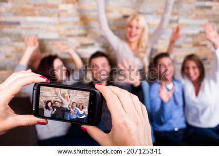 woman taking a photo with her smartphone of their friends