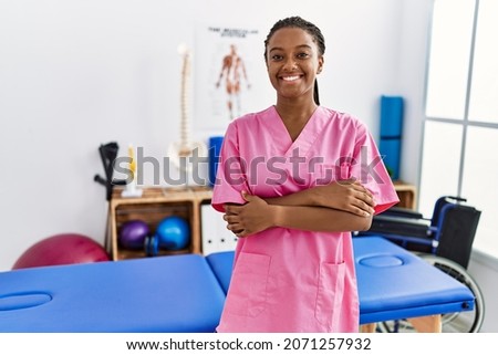 Young african american woman working at pain recovery clinic happy face smiling with crossed arms looking at the camera. positive person. 