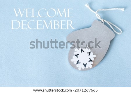 Welcome, December inscription on a blue background next to a wooden mittens, New Year's decoration. Postcard, banner