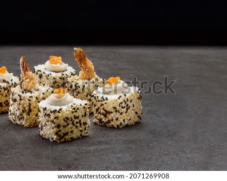 Ebi tempura Japanese sushi roll with black tiger shrimp tails with red salmon caviar on top. Prawn sushi with sesame seeds