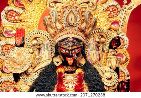 Portrait of Hindu Goddess Kali, heavily decorated with golden ornaments and zari (golden embroidery) works. Photo taken inside a Kali Puja pandal in Kalighat, Kolkata in 2021. Royalty-Free Stock Photo #2071270238