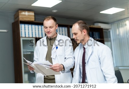 Couple of medical specialists working together. Doctor checking documents with coworker.