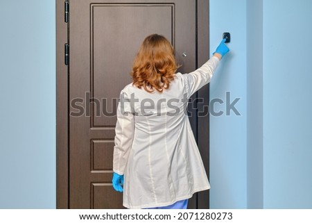 Woman doctor rings the apartment doorbell when visiting a patient home. Royalty-Free Stock Photo #2071280273
