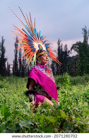 Aztec dancer in the field also known as "Chinampa" in Xochimilco, Mexico, with the traditional Aztec clothing and accessories like "Penachos" or "Huipiles". Royalty-Free Stock Photo #2071280702