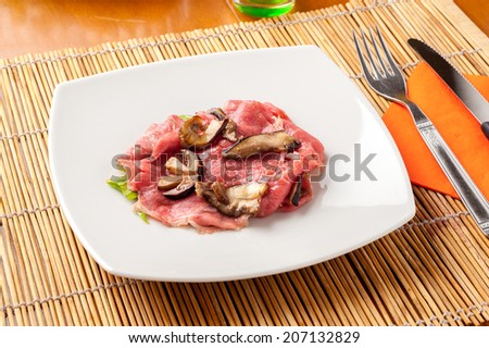 plate of raw meat carpaccio with mushrooms