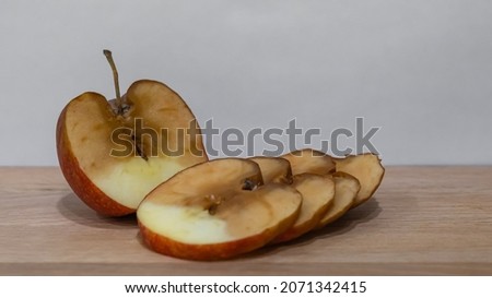 a rotten apple. a slice of rotten fruit. a sliced apple on the table. background picture.
