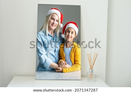 Photo printed on canvas, white background. Happy young family in Santa hats celebrating Christmas at home