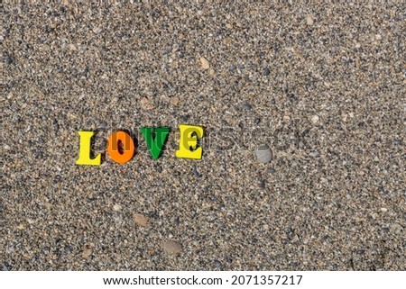 Multicolored inscription Love on the sand. Yellow and blue wooden letters. Romantic caption for a honeymoon. The word love on the beach in the sunlight