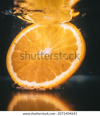 A closeup shot of an orange slice splashing in water
