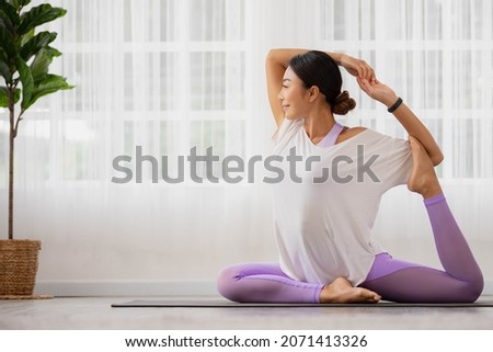 Asian woman practising Eka Pada Rajakapotasana, One Legged King Pigeon position, as part of a yoga concept. Royalty-Free Stock Photo #2071413326