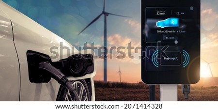 Electric car charging station charging power battery using pump cable, visual display landscape wind turbine sunset background concept. Innovative eco energy resources fuel vehicle transportation.