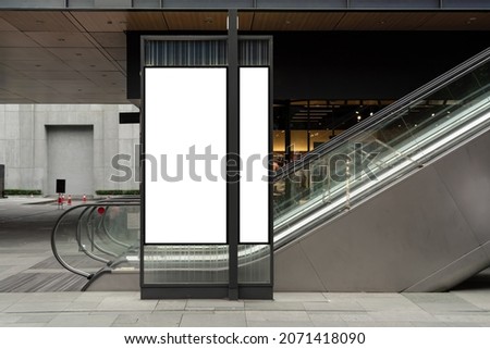 Background advertisement sign mockup blank space, light box stand sign hanging from retail storefront in city town center shopping mall next to escalator, white empty for add business logo advert