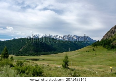 peaks of mountains against the sky with white clouds. Summer day . High snowy peaks in the distance