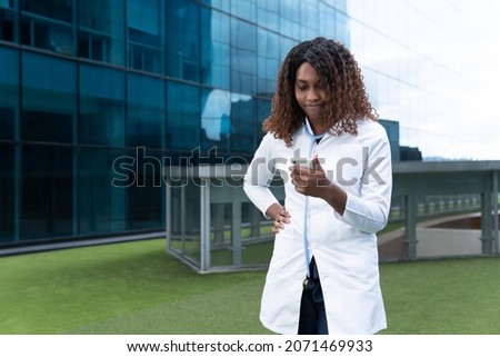 Female doctor watches worried her cell phone in the street. High quality photo