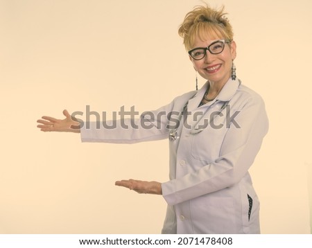 Studio shot of beautiful senior Asian woman doctor with short hair against white background